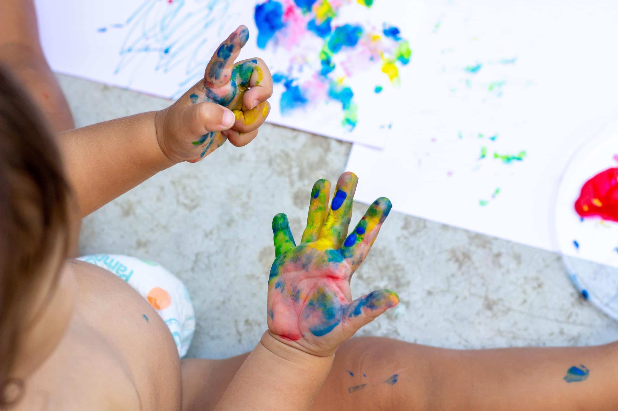 Toddler looking at his hands full of colors because it was ice painting