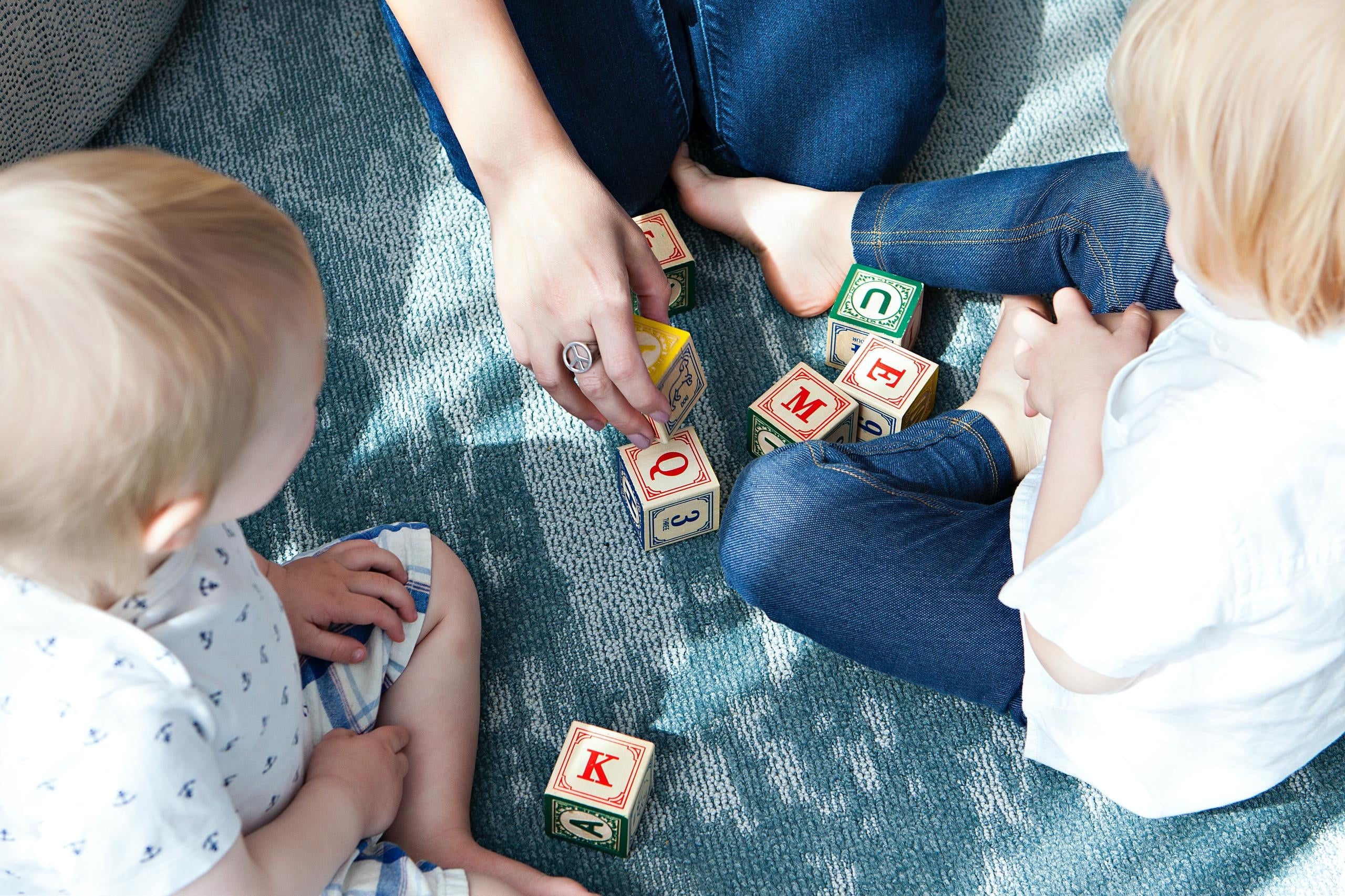 A nanny and two kids playing with letter cubes